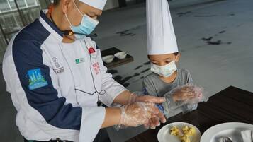 A person in a chef's uniform serving food to a child at a table.