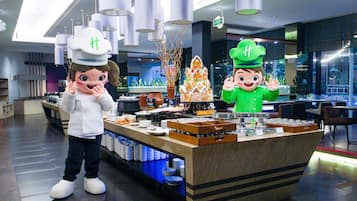 A hotel lobby with a reception desk, a large Christmas tree, and two costumed characters.