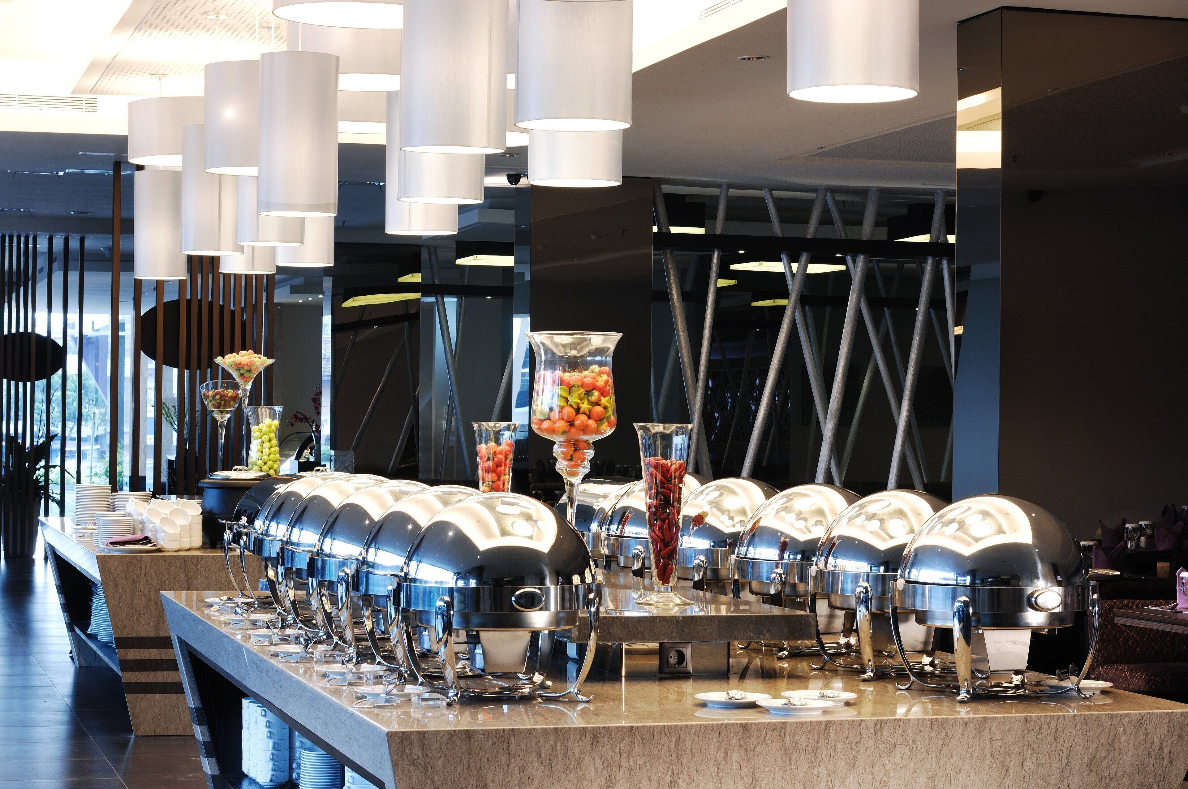 A buffet setup with multiple food dispensers and a variety of fruits and vegetables displayed in clear containers.