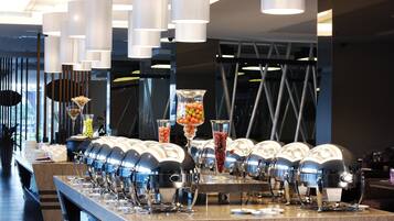 Een buffetopstelling met diverse voedseldispensers en een scala aan fruit en groenten, gepresenteerd in glazen containers.