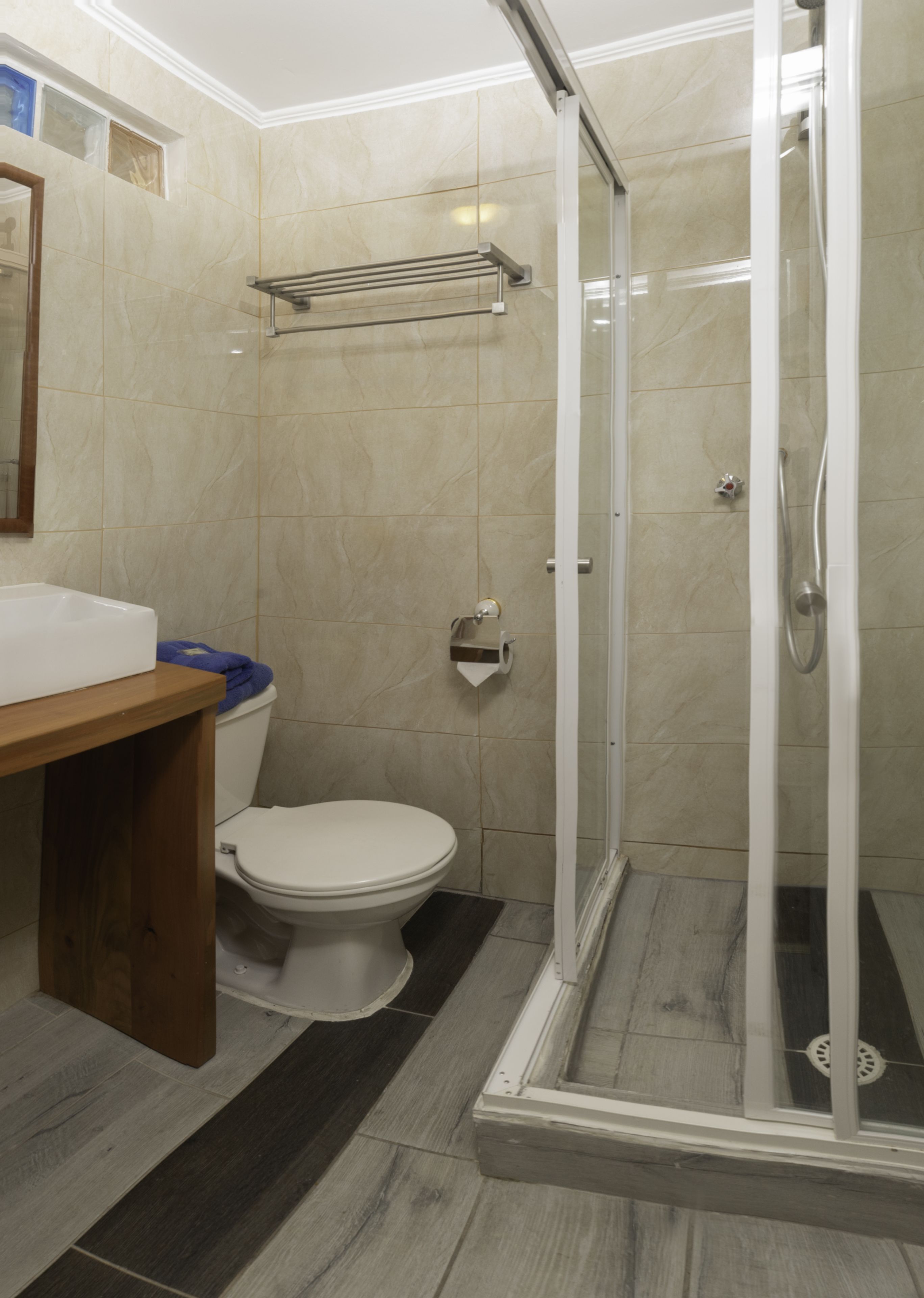 Un baño con inodoro, cabina de ducha y tocador de madera.