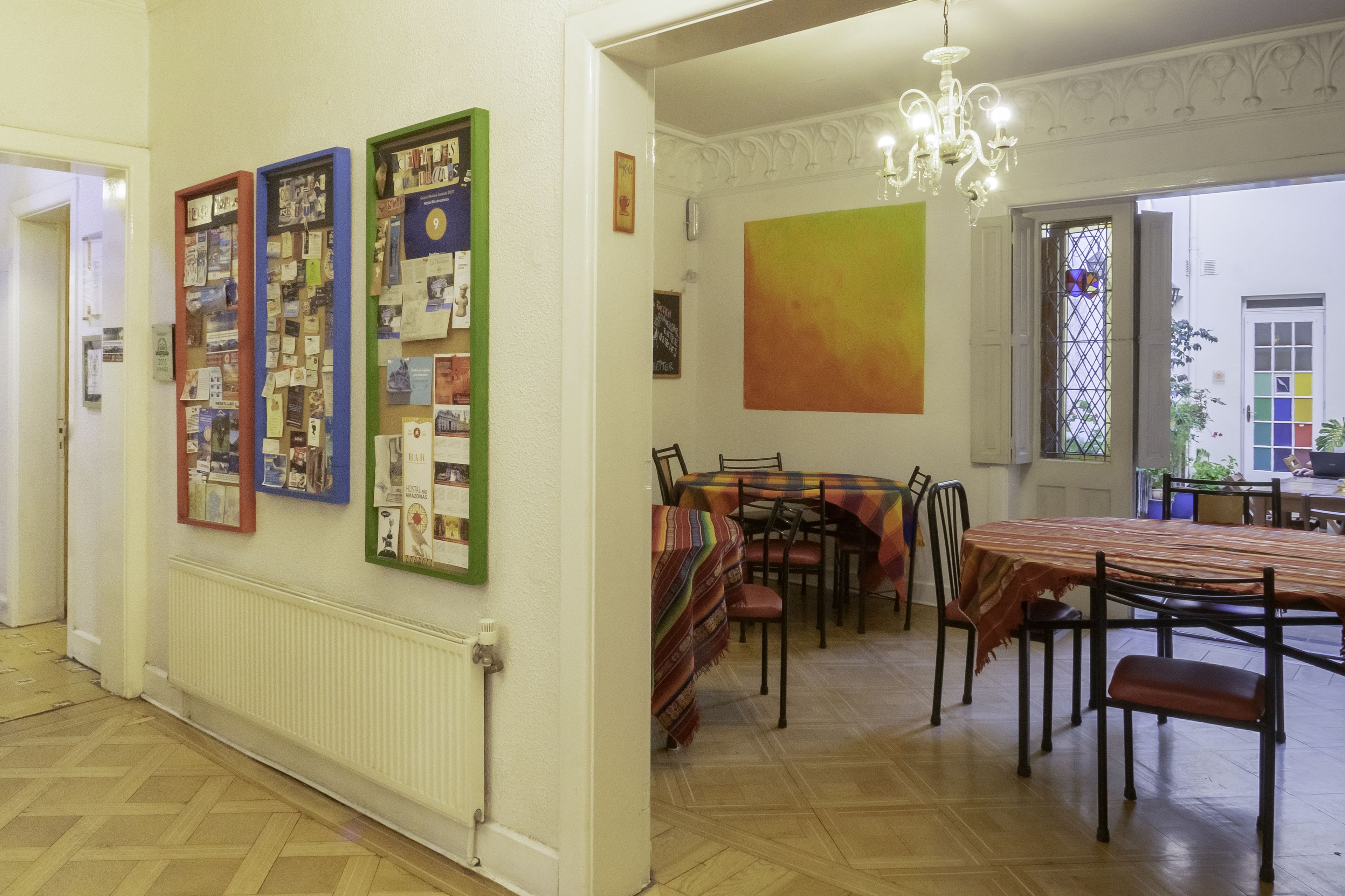 A dining area with a table and chairs, a bulletin board with various papers, and a large abstract painting on the wall.