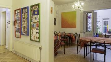 A dining area with a table and chairs, a bulletin board with various papers, and a large abstract painting on the wall.