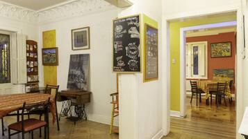 A dining area with a wooden table and chairs, a bookshelf, and a chalkboard menu on the wall.