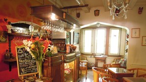 Ein gemütliches Restaurant-Interieur mit Holztischen und -stühlen, einer Bar mit hängenden Gläsern und einer Tafel mit der Speisekarte.