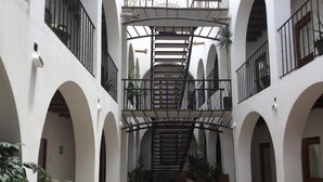 Ein Innenhof mit Holztisch und Stühlen, umgeben von weißen Wänden und Bögen.