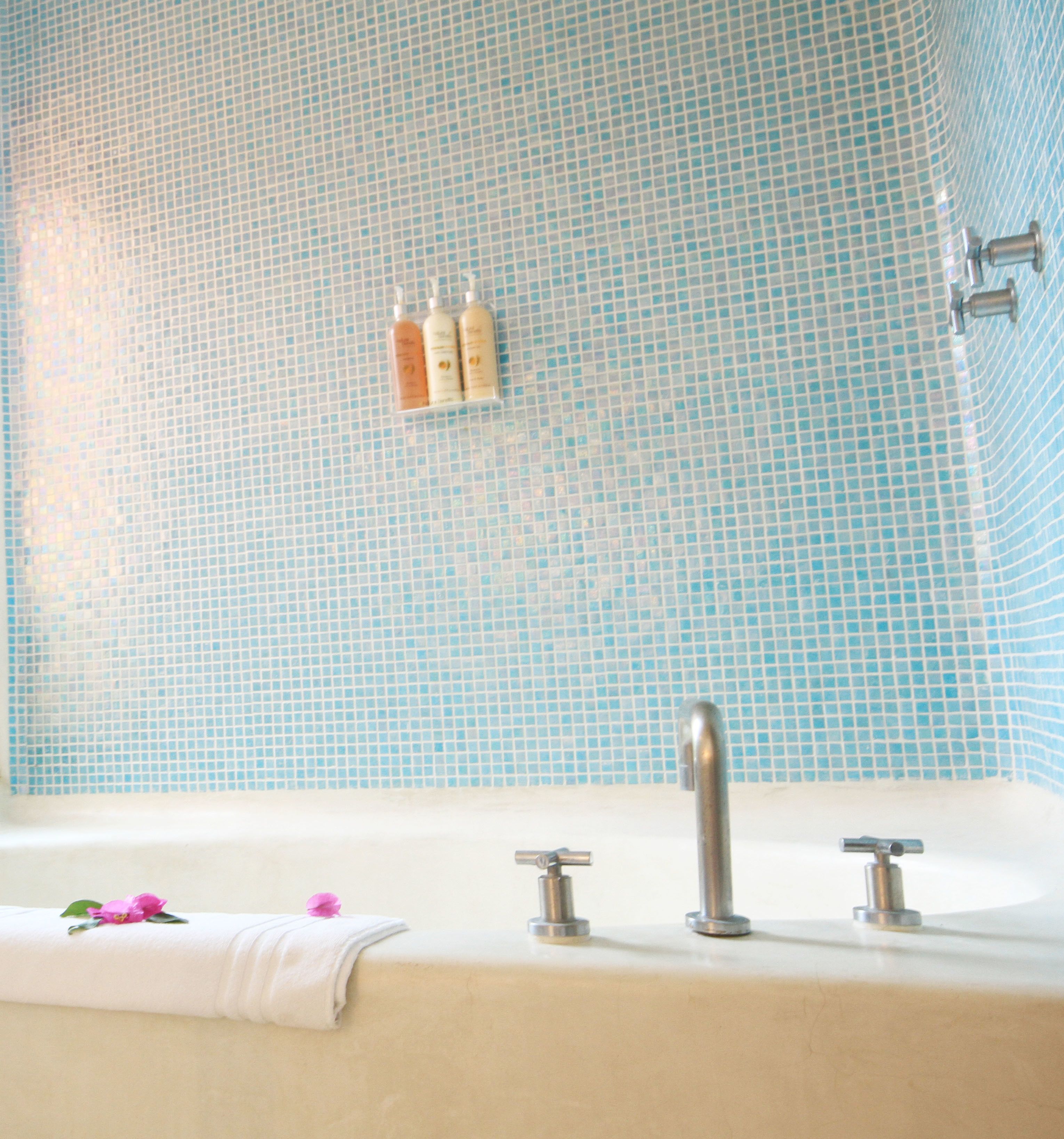 A bathroom with a tiled wall, a bathtub, and a towel with a flower.
