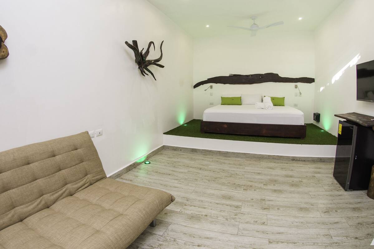 Ein Schlafzimmer mit einem Bett, einem Schlafsofa, einem Spiegel und einem Deckenventilator.