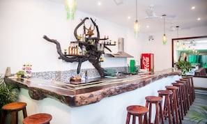 Un espace bar doté d’un îlot en bois, de tabourets et d’une branche d’arbre décorative.