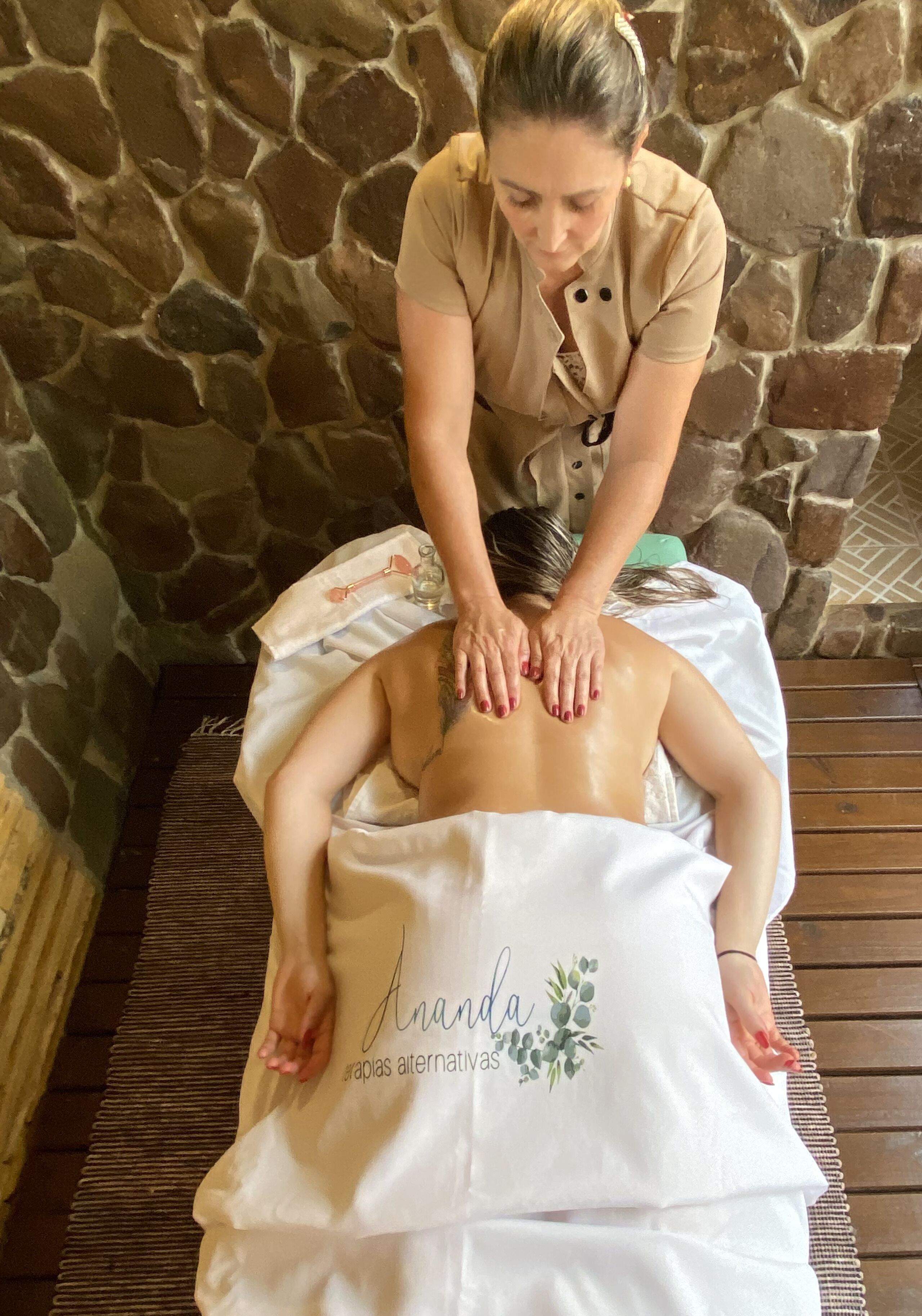 Sessão de massagem em um quarto com paredes de pedra e piso de madeira.