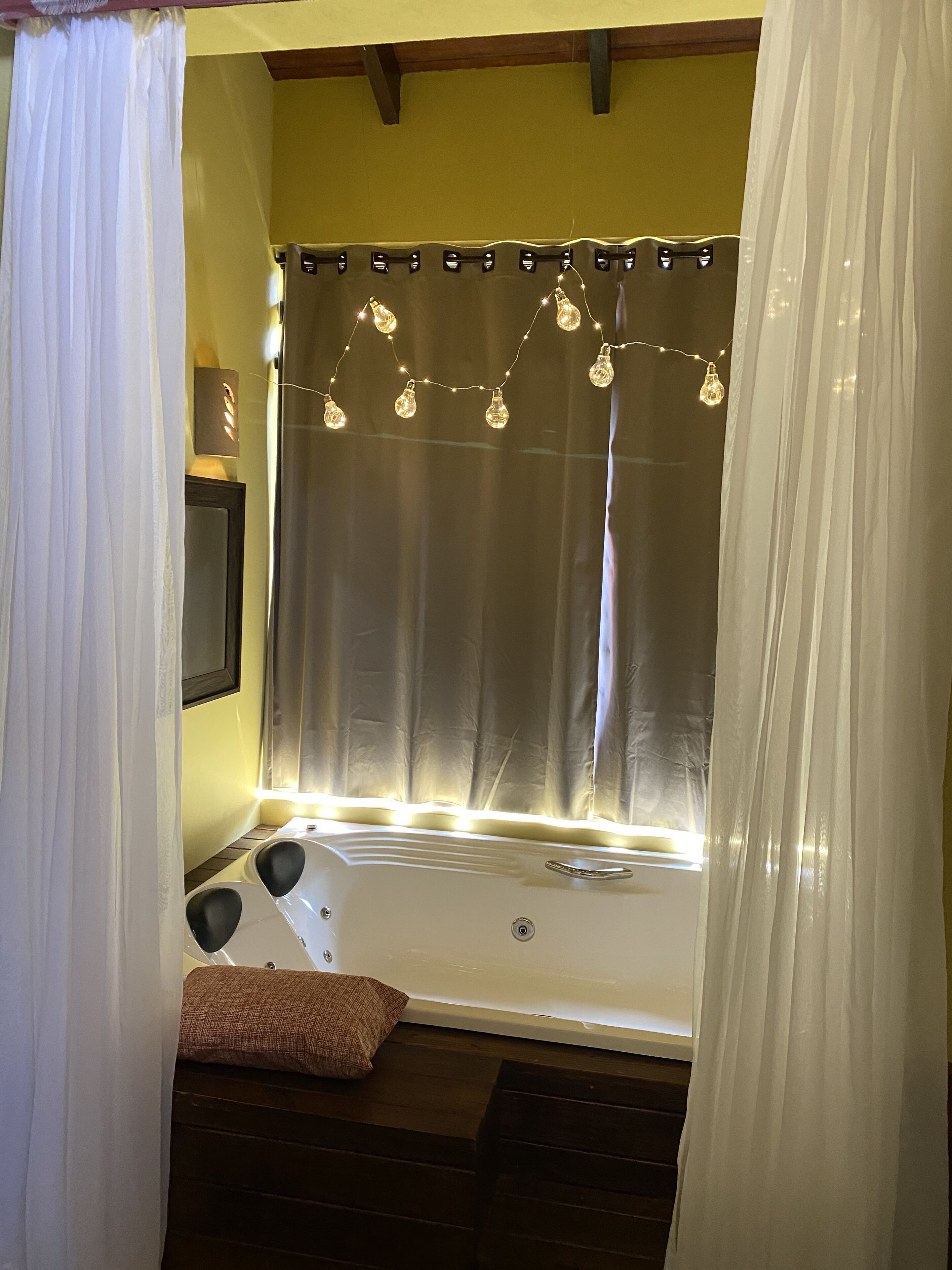 A spa room with a bathtub, a towel, and a curtain.