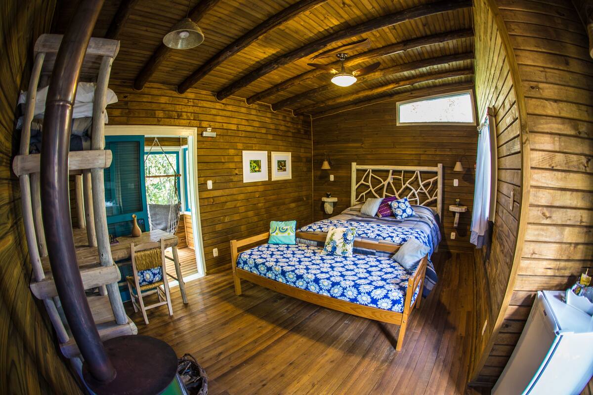 Una habitación de cabaña de madera con una cama, un escritorio y una silla.