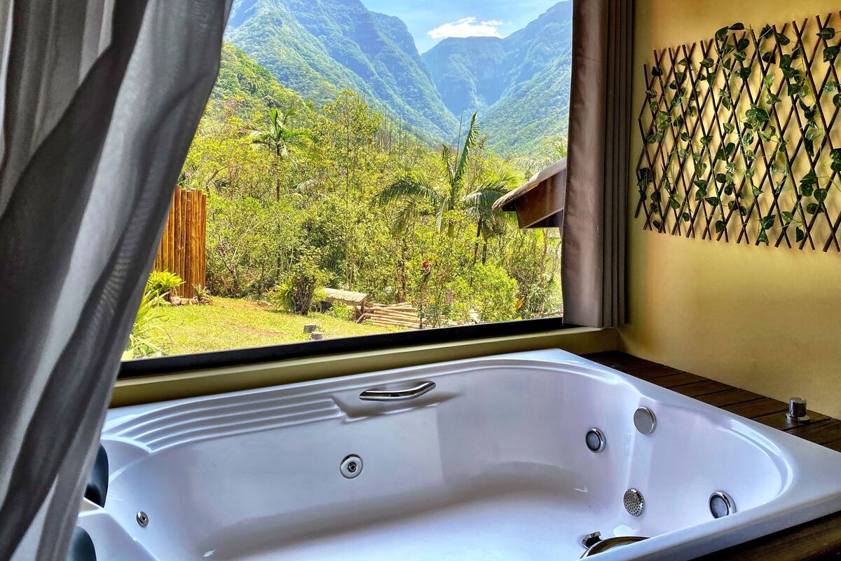 Un baño con una bañera grande y vistas a un paisaje montañoso a través de una ventana.