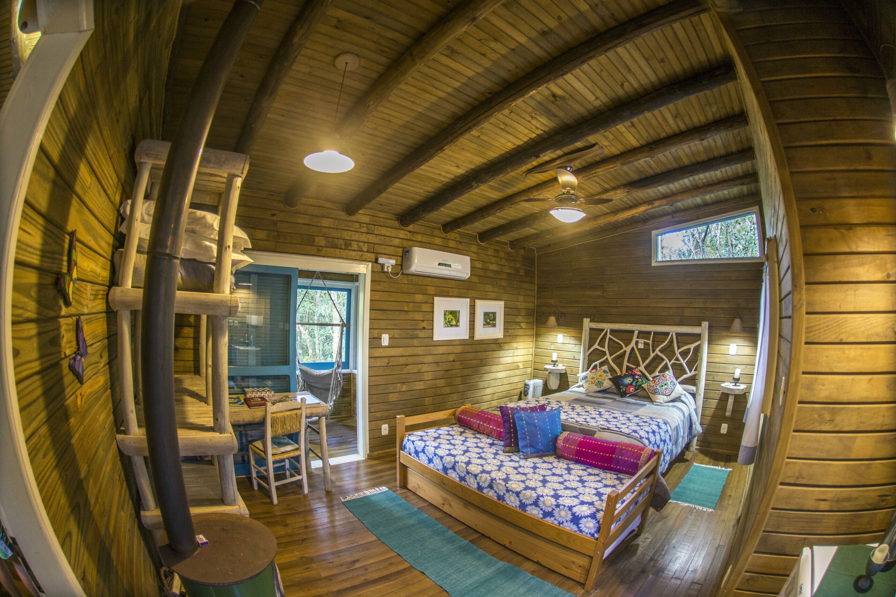 A wooden cabin bedroom with a bed, a desk, and a chair.