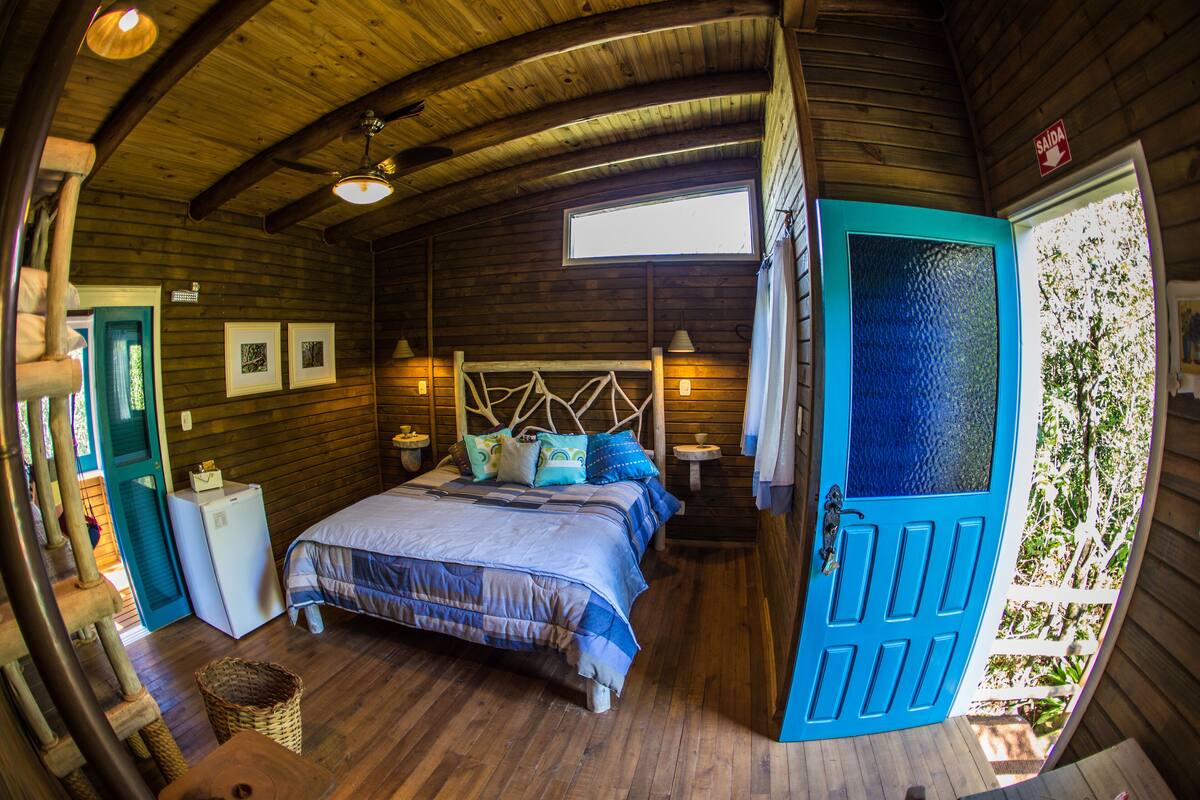 Acogedora habitación de cabaña de madera con una cama, una mesita y una ventana.