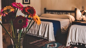 Ein Zimmer mit zwei Betten, einer Kandelaber und einer Vase mit Blumen auf einem Tisch.