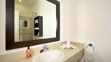 A bathroom with a white sink, a dark-framed mirror, a towel rack, and a bottle of soap.