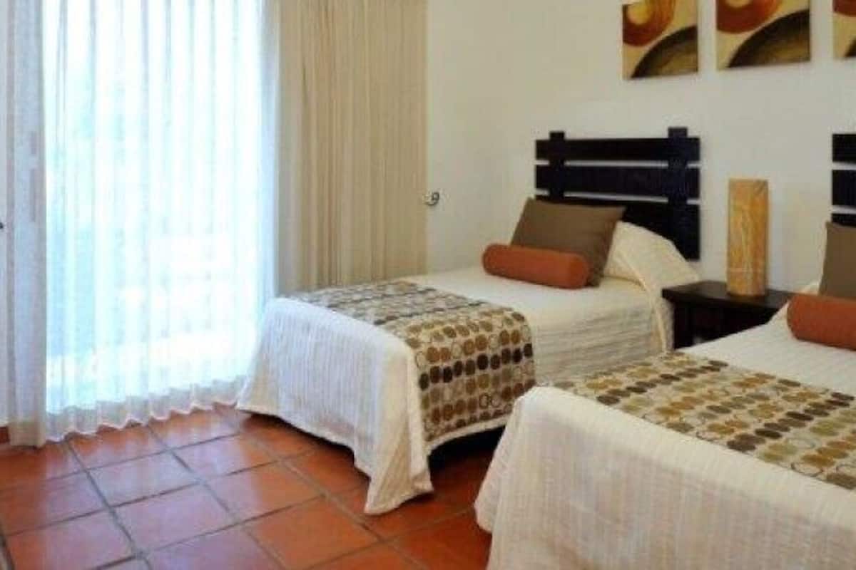 Een hotelkamer met twee bedden, een televisie en een raam met gordijnen.