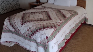 Una habitación de hotel con cama, mesita de noche, lámpara y un papel tapiz con diseño.