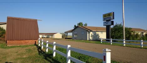 A rural motel with a white fence, a brown building, and a clear blue sky.