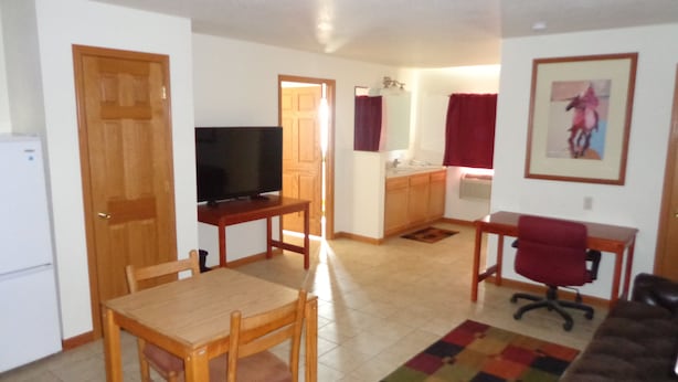 Un espacio habitable compacto con comedor, kitchenette, televisor y sofá.