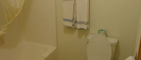 A bathroom with a bathtub, toilet, and a framed picture on the wall.