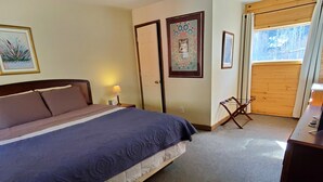 A bedroom with a large bed, a wooden door, and a window with a view of trees. - Kenosha Lodge (Grant)