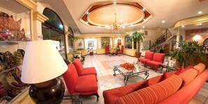 A spacious living area with a chandelier, red sofas, and a coffee table.