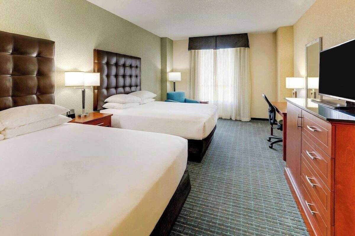 Ein Hotelzimmer mit zwei Betten, einem Schreibtisch, einem Fernseher und einem Schminktisch.
