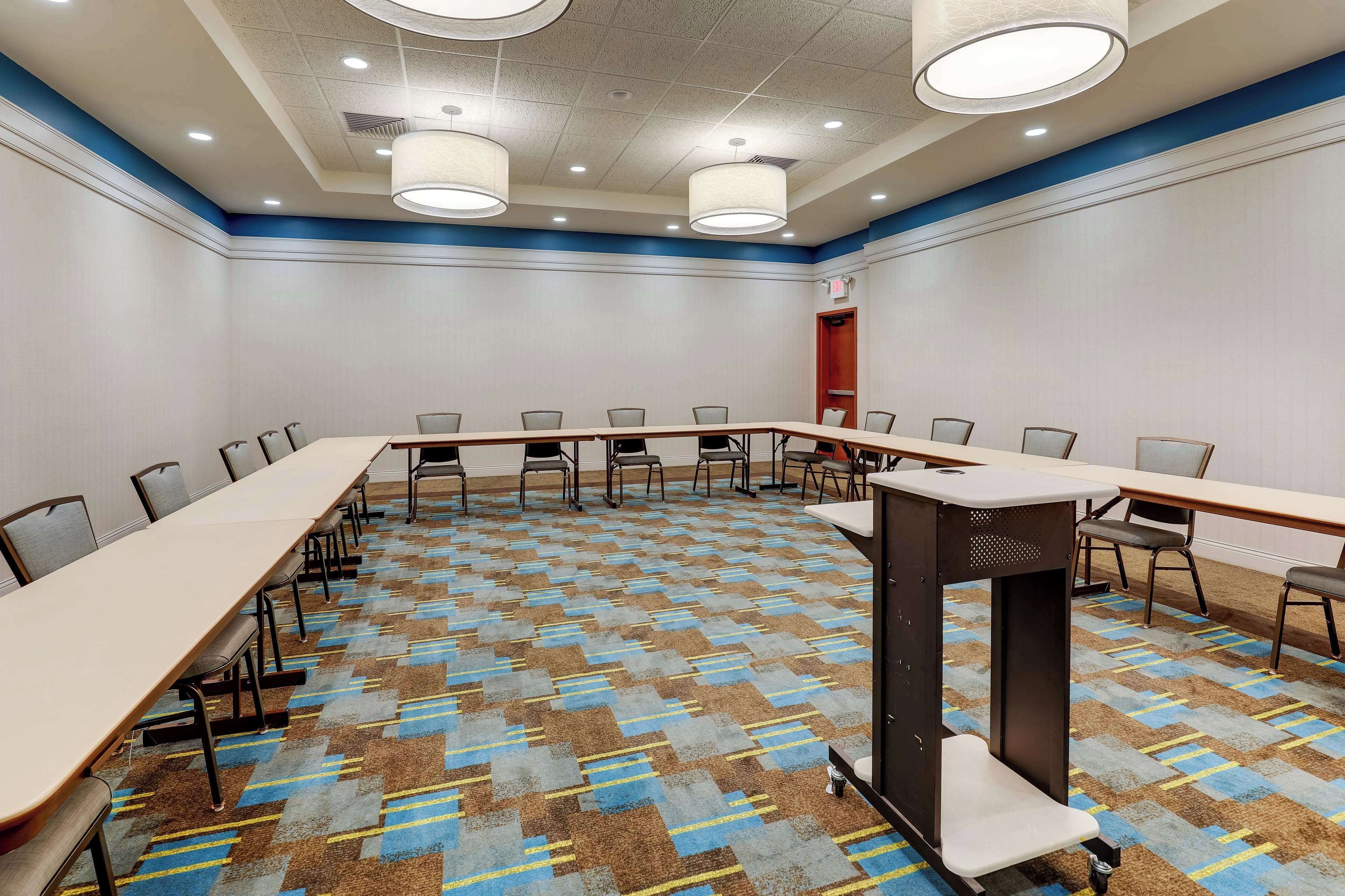A conference room with a long table, chairs, and a carpeted floor.