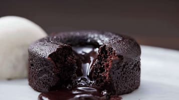A chocolate lava cake with a gooey center and a scoop of vanilla ice cream beside it.