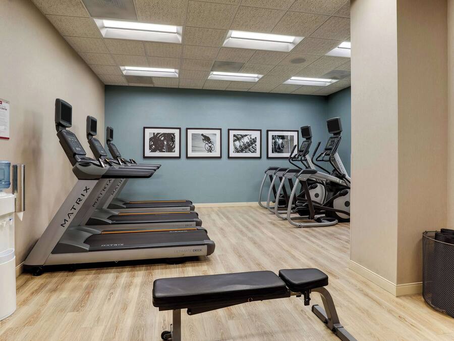 A gym with treadmills, stationary bikes, and a bench.