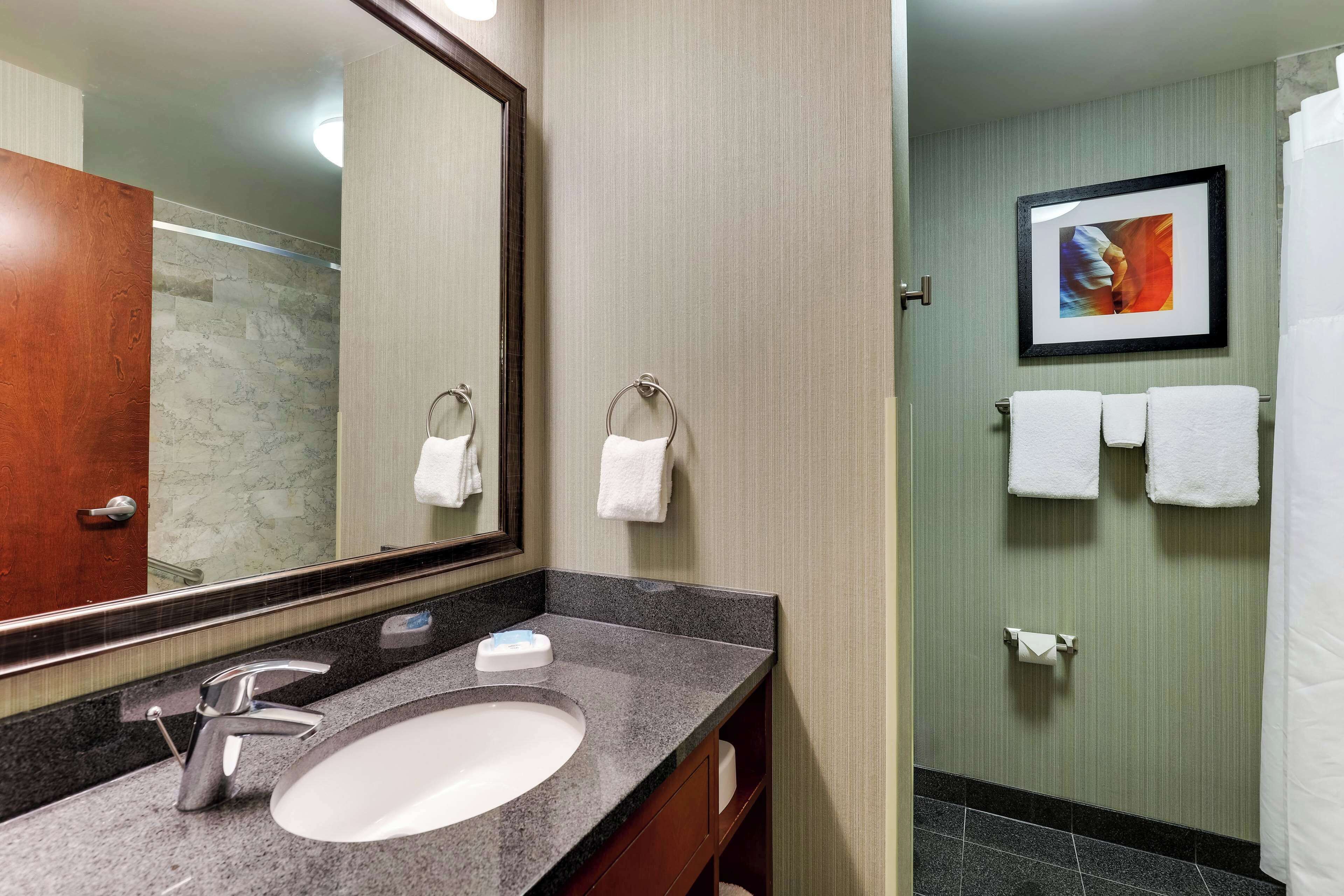 A bathroom with a marble sink, a mirror, and a framed picture on the wall.