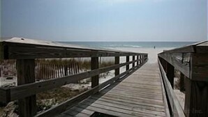 A wooden boardwalk leading to a beach with a clear sky. - SunSwept 505 by ALBVR (Orange Beach)