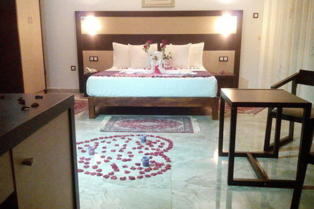 A hotel room with a bed, bedside tables, a chair, a decorative rug, and a small table.