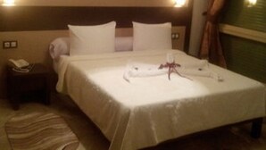 A hotel room with a bed, bedside table, and a nightstand. - Telemly Hotel (Algiers)