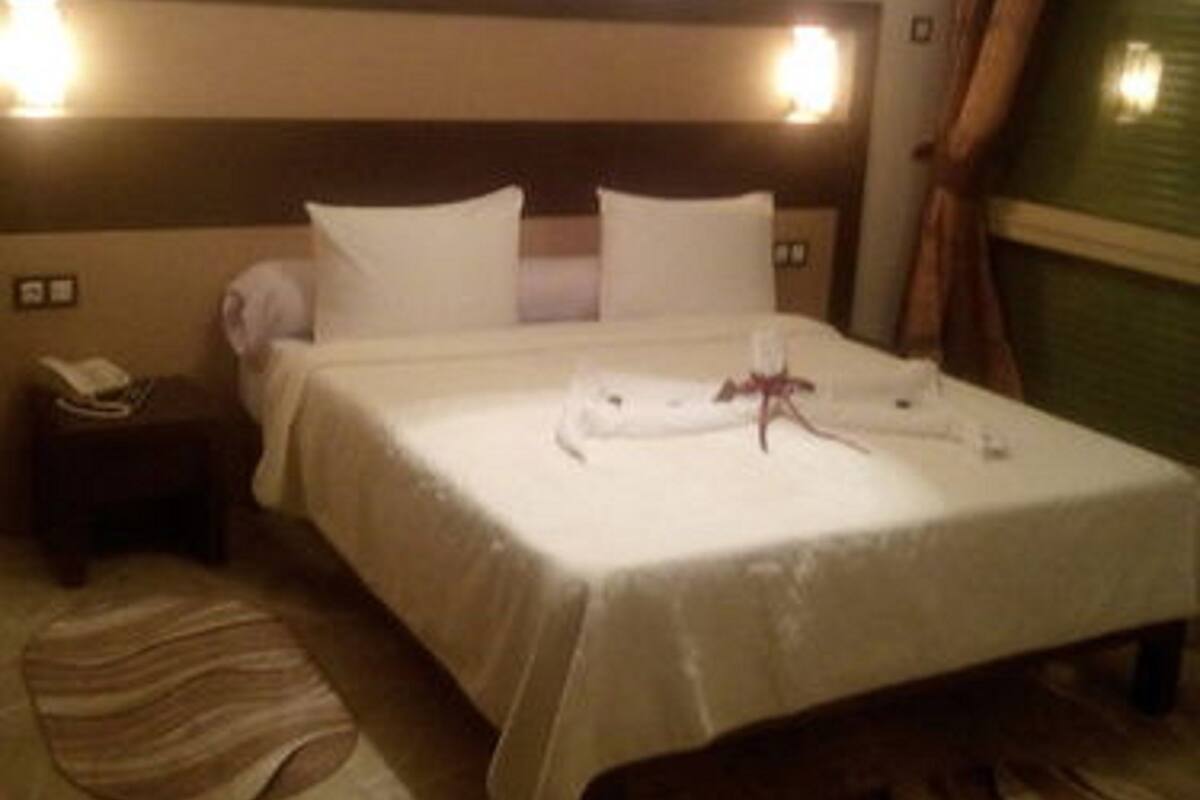A hotel room with a bed, bedside table, and a nightstand.