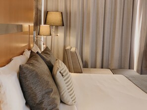 A hotel room with a bed, pillows, a nightstand, a lamp, and curtains. - Hotel Mercury Inn (Querétaro)