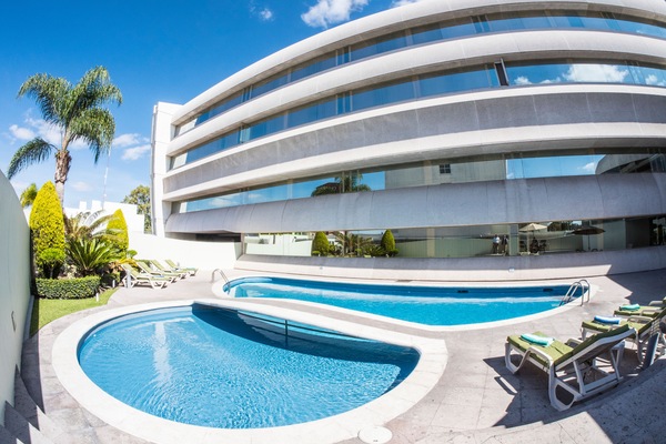 Una piscina al aire libre, sillones reclinables de piscina