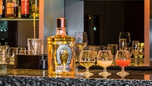 A bar area with various liquor bottles and glasses on shelves. - Hotel Mercury Inn (Querétaro)