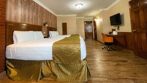 A hotel room with a large bed, a desk, a chair, a television, and a door leading to another room. - The Architect (Washington)