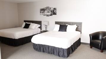 Two single beds with dark headboards, a black leather armchair, and a wall-mounted lamp.