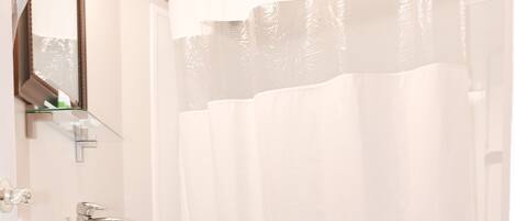 A bathroom with a white sink, dark cabinet, white toilet, and a shower curtain.
