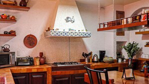 Una cocina con estufa, microondas y varios utensilios de cocina. Hay un colgador para ollas sobre la estufa.