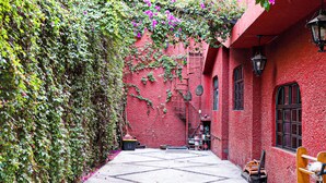 Un callejón estrecho con un edificio rojo, un banco de madera y una escalera de metal.