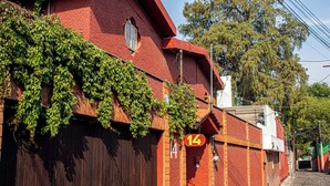 Un edificio de ladrillo rojo con hiedra en la pared, una puerta de madera y un letrero con el número 14.