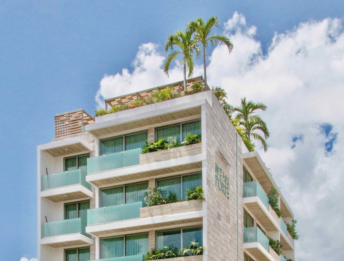 A view of the exterior of Newport House Playa del Carmen Boutique Hotel with balconies and plants