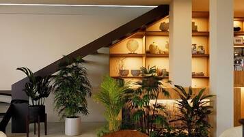A modern interior with a staircase, seating area, and a plant-filled corner.