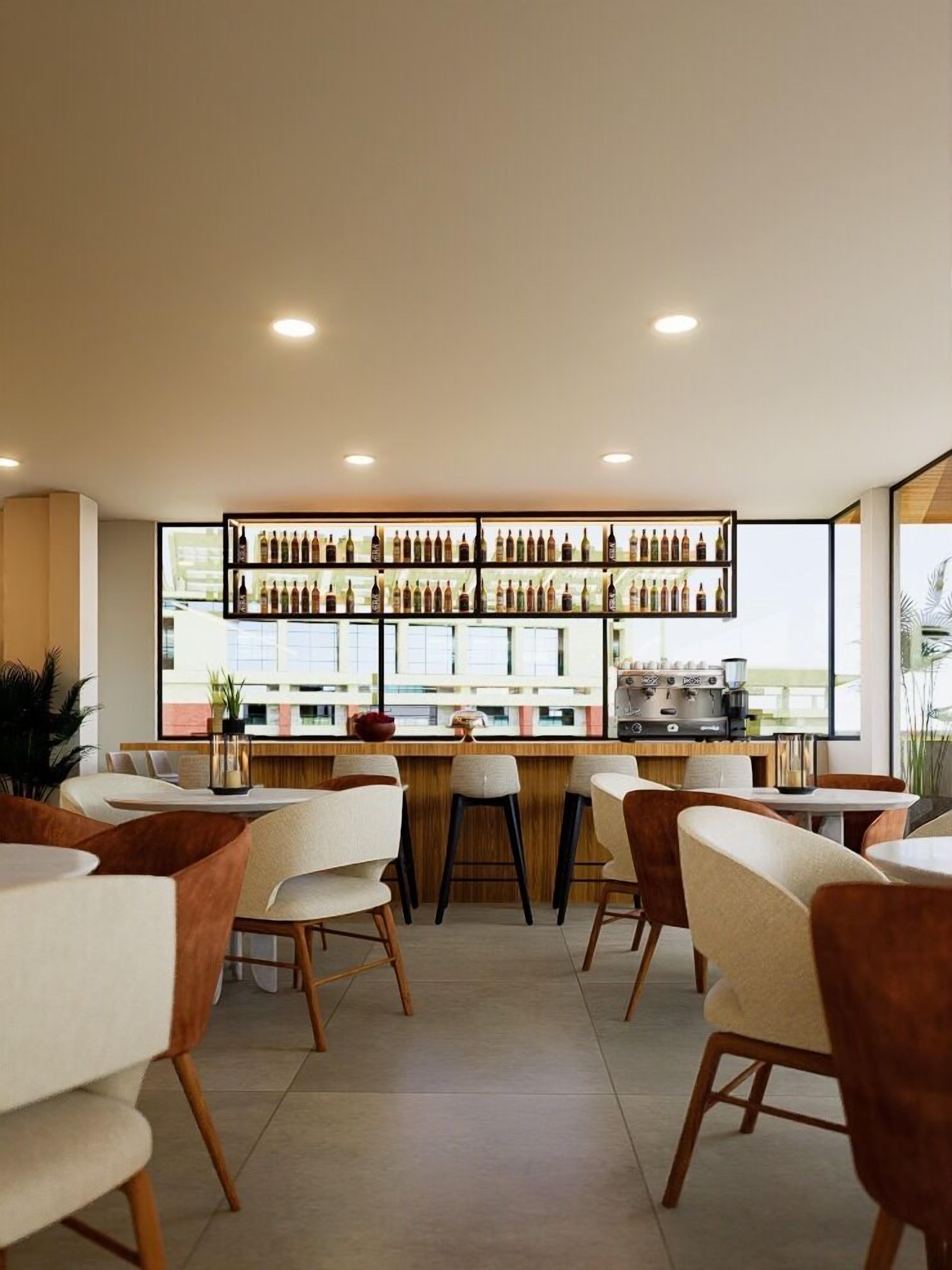 Eine moderne Bar mit mehreren Flaschenregalen, einer Kaffeemaschine und Sitzgelegenheiten mit Blick auf die Stadt.