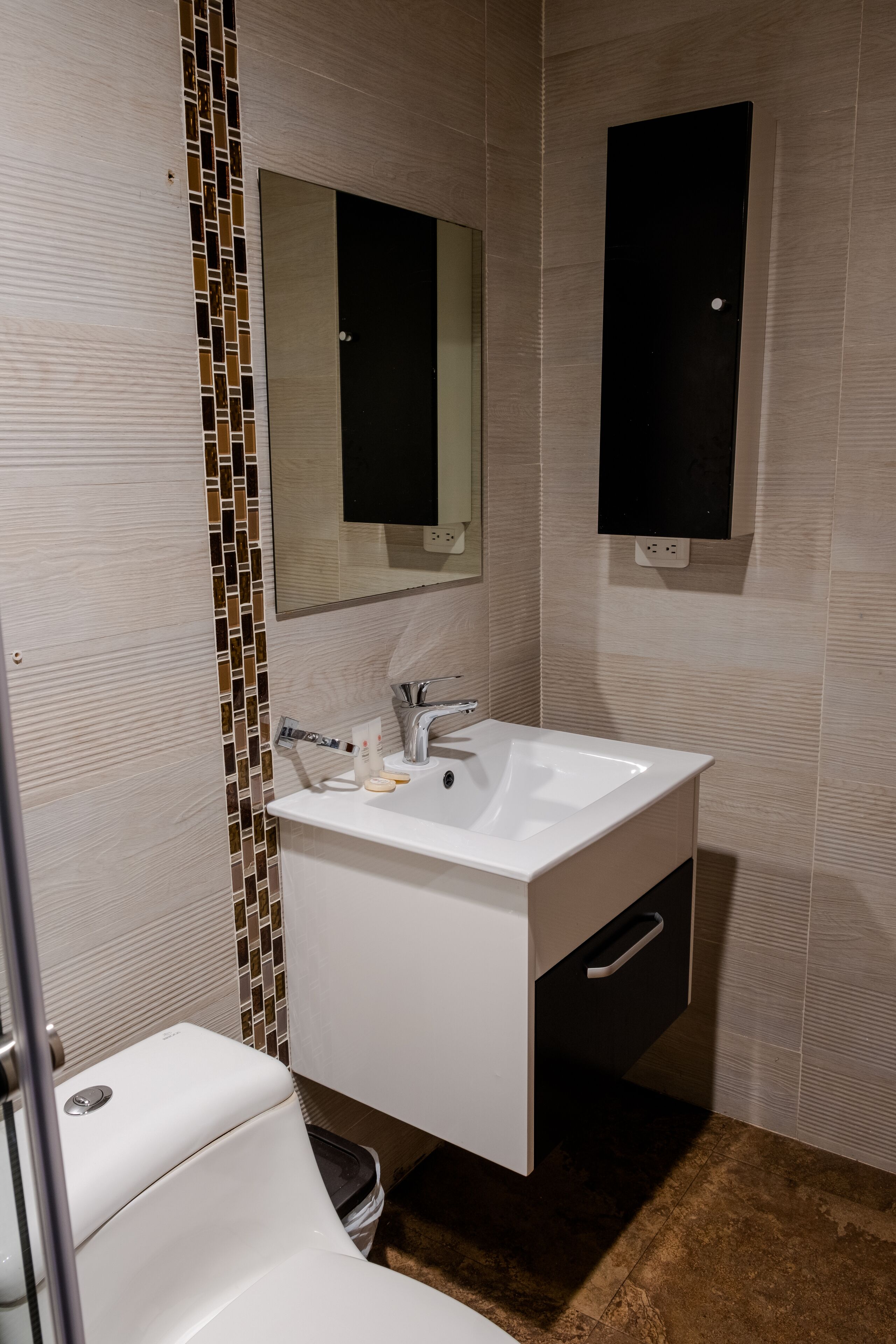 Un baño moderno con un lavamanos blanco, un espejo y un revoque de azulejos.